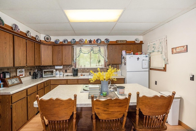 4424 Teal Ln, Newaygo, MI 49337 - kitchen with freestanding refrigerator, a paneled ceiling, light countertops, light wood-style flooring, and decorative backsplash