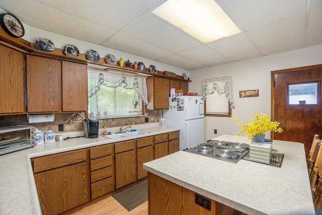 4424 Teal Ln, Newaygo, MI 49337 - kitchen featuring freestanding refrigerator, a drop ceiling, brown cabinetry, light countertops, and backsplash