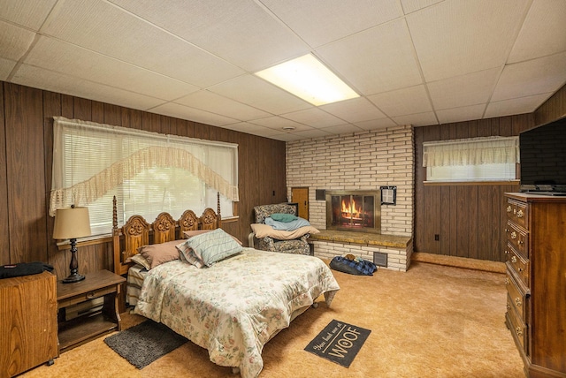 4424 Teal Ln, Newaygo, MI 49337 - bedroom featuring multiple windows, wood walls, a brick fireplace, light colored carpet, and a drop ceiling