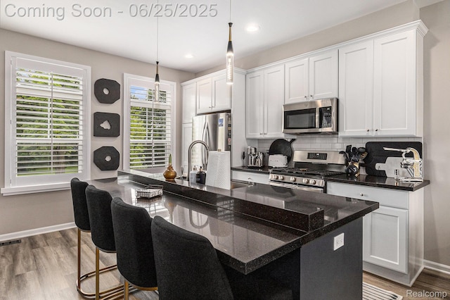 475 Jenny Way, Brighton, MI 48116 - kitchen with stainless steel appliances, tasteful backsplash, white cabinetry, wood finished floors, and hanging light fixtures