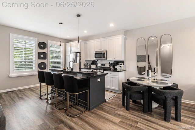 475 Jenny Way, Brighton, MI 48116 - kitchen featuring appliances with stainless steel finishes, dark countertops, a kitchen bar, dark wood-style flooring, and recessed lighting