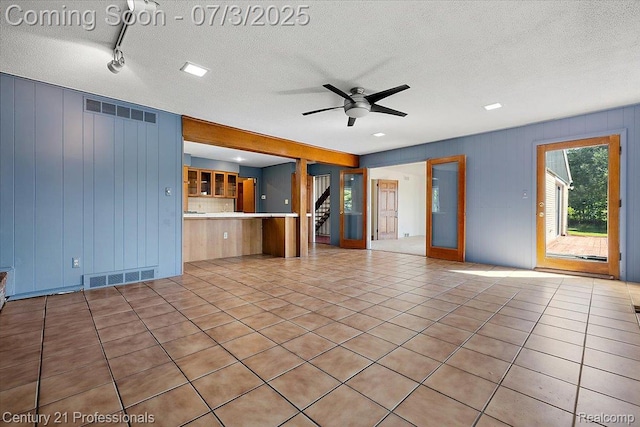 291 N Baldwin Rd, Clarkston, MI 48348 - unfurnished living room featuring a ceiling fan, a textured ceiling, light tile patterned floors, stairway, and rail lighting