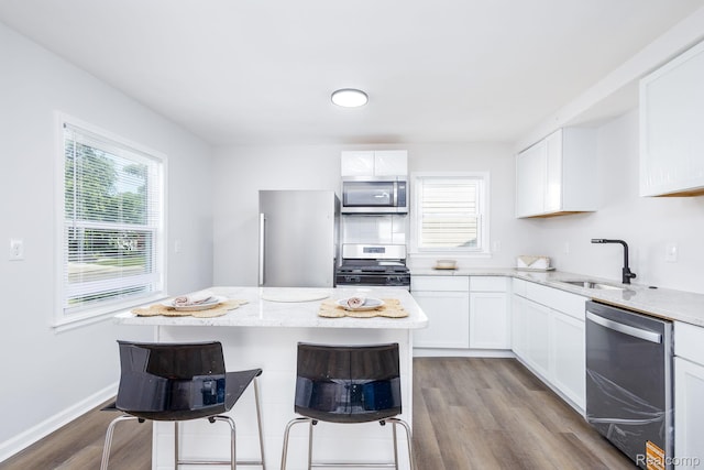 1730 E Hazelhurst St, Ferndale, MI 48220 - kitchen with stainless steel appliances, wood finished floors, white cabinetry, and a breakfast bar area