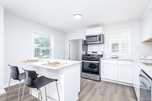 1730 E Hazelhurst St, Ferndale, MI 48220 - kitchen featuring appliances with stainless steel finishes, light wood-type flooring, light stone countertops, and white cabinetry