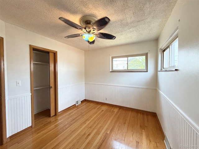 8121 Marian St, Warren, MI 48093 - unfurnished bedroom featuring light wood-style floors, a wainscoted wall, a textured ceiling, ceiling fan, and a closet