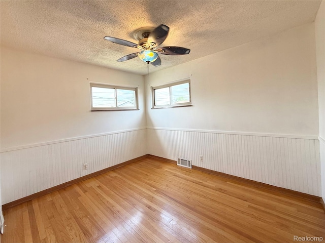 8121 Marian St, Warren, MI 48093 - empty room featuring light wood finished floors, a textured ceiling, a wainscoted wall, and ceiling fan