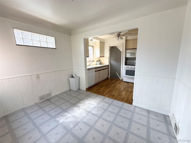8121 Marian St, Warren, MI 48093 - kitchen with white appliances, wainscoting, a ceiling fan, light countertops, and light flooring