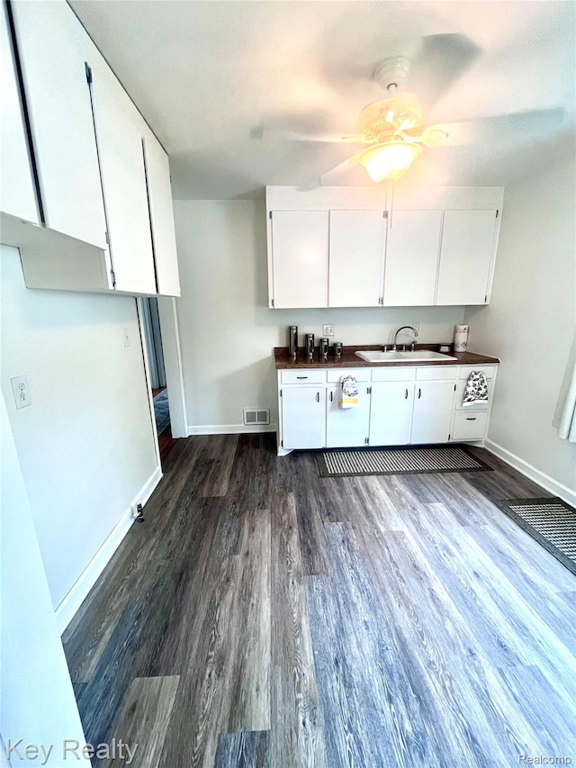 13509 Backus St, Southgate, MI 48195 - kitchen with dark countertops, white cabinets, and dark wood-style flooring