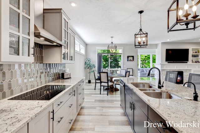 8205 Autumn Acres Dr, Rockford, MI 49341 - kitchen featuring wall chimney exhaust hood, black electric cooktop, light wood-style flooring, decorative backsplash, and light stone counters