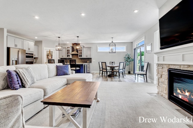 8205 Autumn Acres Dr, Rockford, MI 49341 - living area with a chandelier, recessed lighting, a fireplace, and light wood finished floors