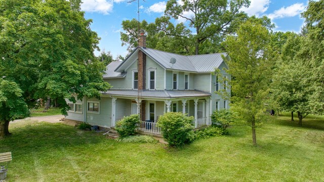 15379 Howard Rd, Hanover, MI 49241 - view of home's exterior with a porch, a chimney, a lawn, and a metal roof
