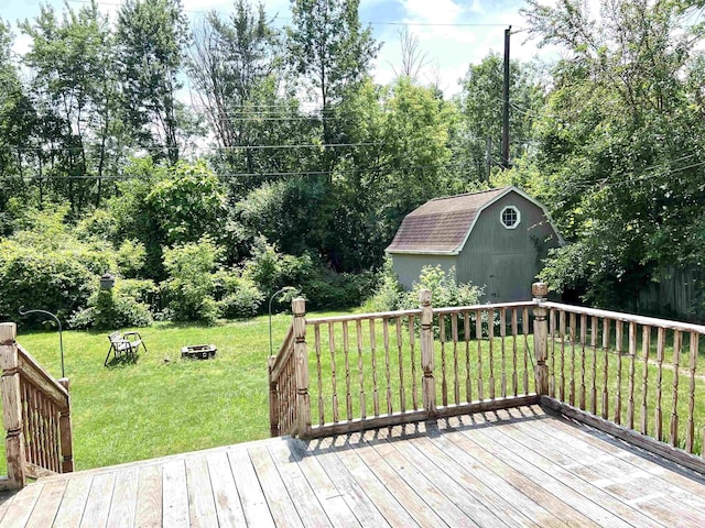 5425 Westchester Dr, Flint, MI 48532 - wooden deck featuring a storage shed, a fire pit, a lawn, and view of wooded area