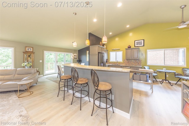 285 Ash Ct, South Lyon, MI 48178 - kitchen with light wood-style floors, stainless steel fridge with ice dispenser, open floor plan, a kitchen breakfast bar, and high vaulted ceiling