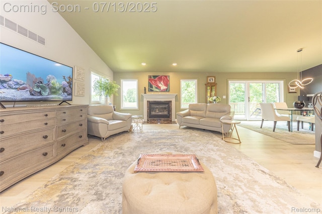 285 Ash Ct, South Lyon, MI 48178 - living room featuring wood finished floors, plenty of natural light, a glass covered fireplace, a chandelier, and recessed lighting