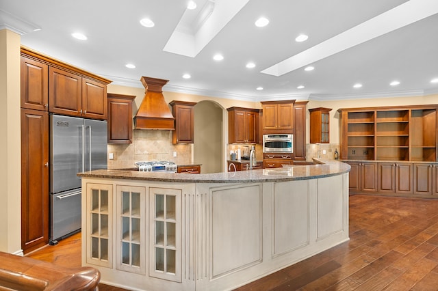 1431 Edgemoor Ave, Kalamazoo, MI 49008 - kitchen featuring custom range hood, appliances with stainless steel finishes, crown molding, light stone countertops, and a spacious island