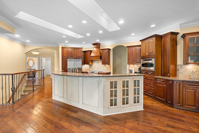 1431 Edgemoor Ave, Kalamazoo, MI 49008 - kitchen featuring arched walkways, stainless steel built in refrigerator, crown molding, a large island, and custom range hood