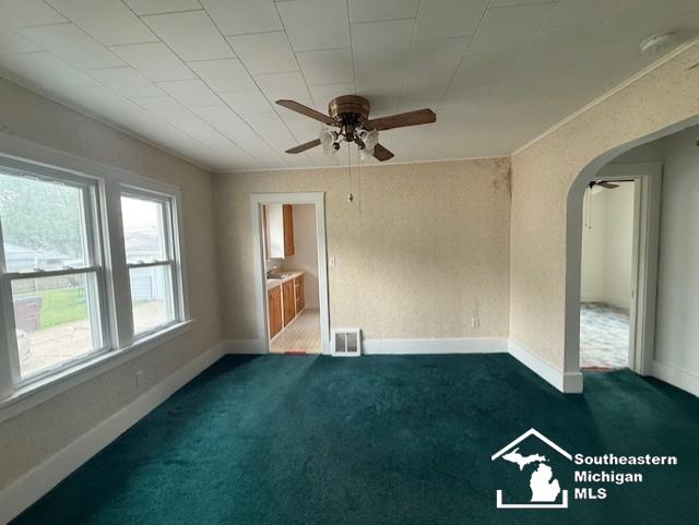 211 Huber Dr, Monroe, MI 48162 - empty room featuring ceiling fan, arched walkways, and dark colored carpet