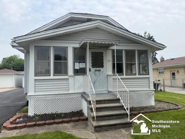 211 Huber Dr, Monroe, MI 48162 - view of front facade with a sunroom, an outbuilding, and a garage
