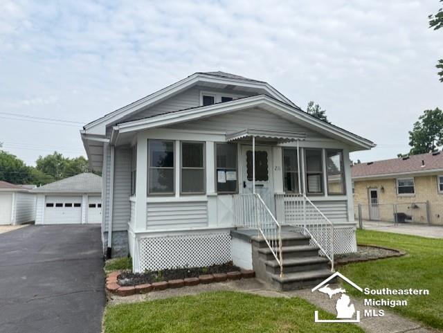 211 Huber Dr, Monroe, MI 48162 - view of front of home featuring a detached garage, an outbuilding, a sunroom, and a front yard