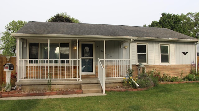 9262 Washington St, Romulus, MI 48174 - view of front facade with roof with shingles, a porch, board and batten siding, and stone siding
