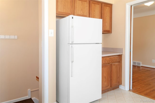 16555 Juliana Ave, Eastpointe, MI 48021 - kitchen featuring freestanding refrigerator, light countertops, brown cabinetry, and light wood-style floors