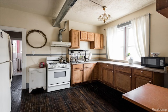 7824 Mount Elliott St, Detroit, MI 48211 - kitchen featuring white appliances, wall chimney exhaust hood, dark wood-style flooring, and a chandelier