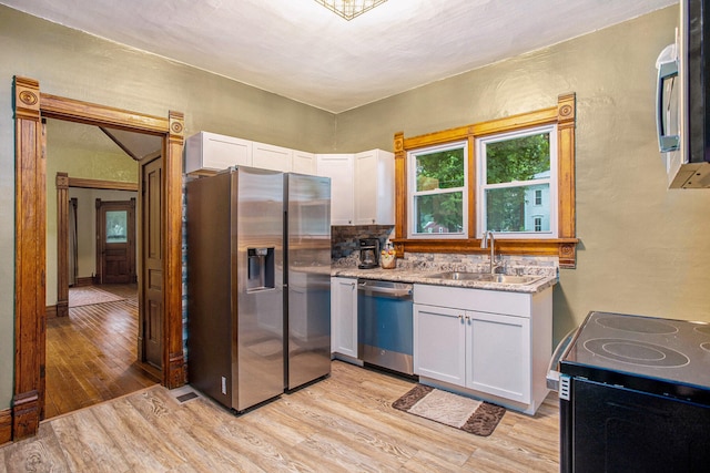 803 N Church St, Tekonsha, MI 49092 - kitchen with appliances with stainless steel finishes, light wood finished floors, white cabinetry, light stone countertops, and tasteful backsplash