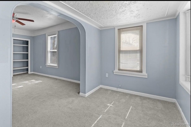 21916 Oakwood Ave, Washington, MI 48021 - unfurnished room featuring a textured ceiling, ceiling fan, carpet flooring, arched walkways, and ornamental molding
