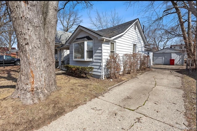 21916 Oakwood Ave, Washington, MI 48021 - view of side of property with a garage, driveway, an outdoor structure, and roof with shingles