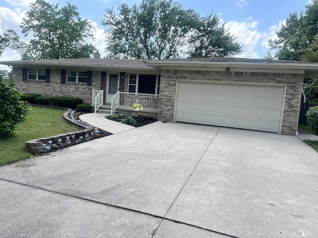 928 S Raisinville Rd, Monroe, MI 48161 - ranch-style house with concrete driveway, brick siding, a garage, a front lawn, and a porch