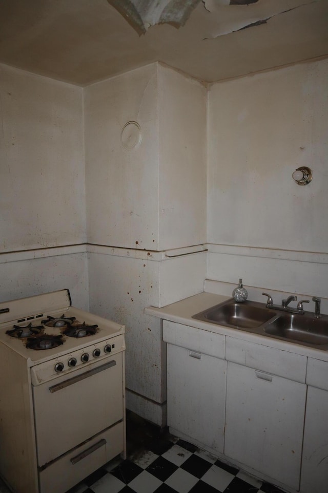 5523 Oregon St, Detroit, MI 48204 - kitchen with white gas stove, tile patterned floors, white cabinetry, and light countertops