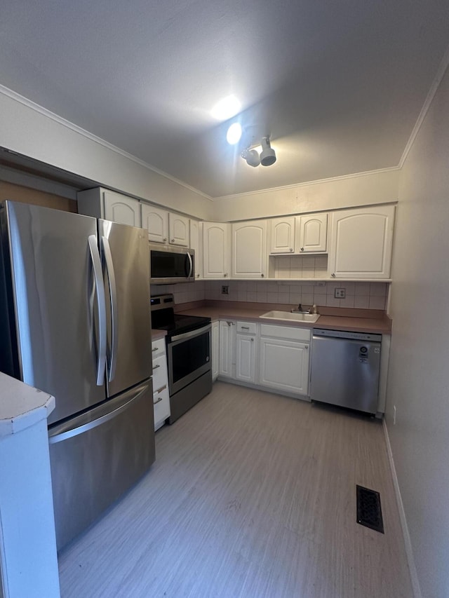 3002 Seaton Circuit N, Warren, MI 48091 - kitchen with stainless steel appliances, white cabinetry, crown molding, tasteful backsplash, and light wood finished floors