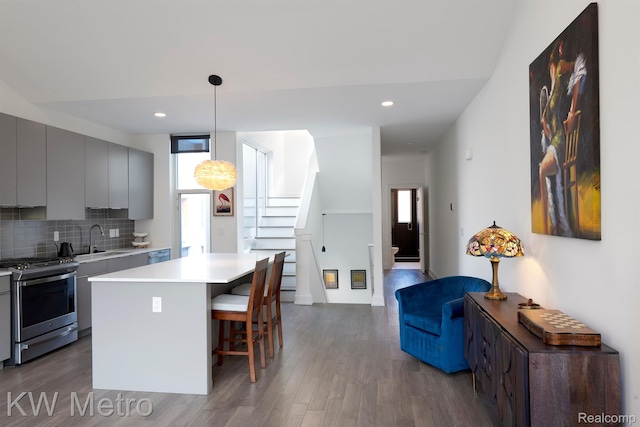 2821 Brush St, Detroit, MI 48201 - kitchen featuring stainless steel range with gas stovetop, gray cabinetry, wood finished floors, light countertops, and a breakfast bar area