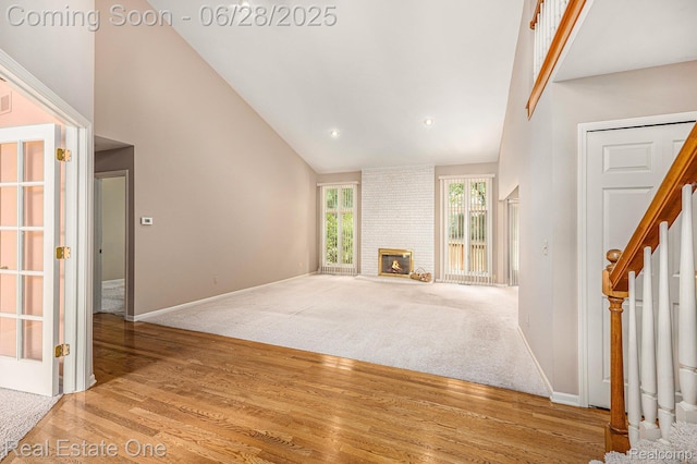 2184 Reagan Dr, Rochester Hills, MI 48309 - unfurnished living room featuring high vaulted ceiling, wood finished floors, stairs, and a brick fireplace