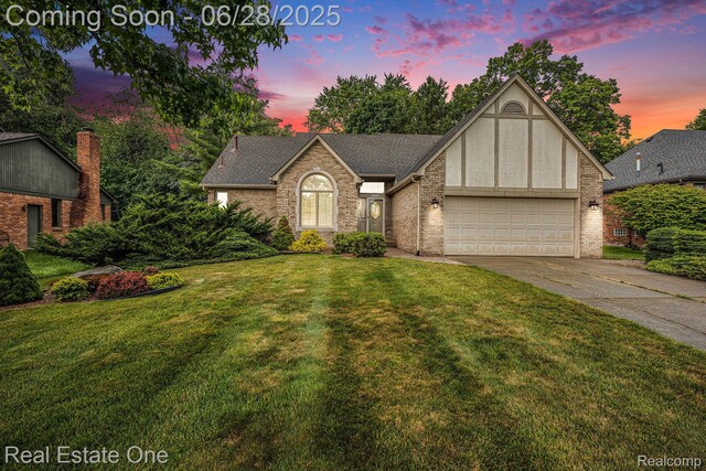 2184 Reagan Dr, Rochester Hills, MI 48309 - view of front of home with an attached garage, driveway, a yard, brick siding, and a shingled roof