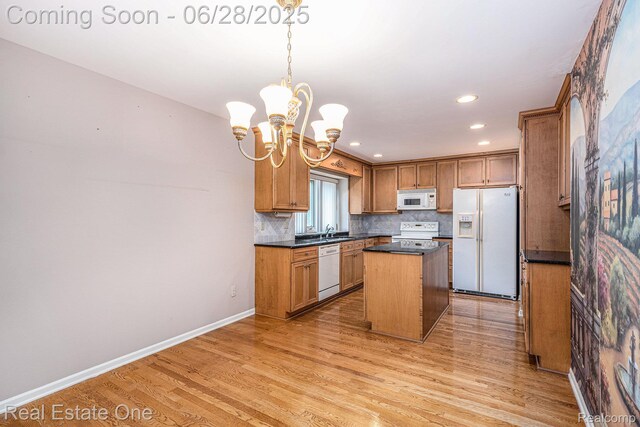 2184 Reagan Dr, Rochester Hills, MI 48309 - kitchen with white appliances, dark countertops, a chandelier, light wood-style floors, and a center island
