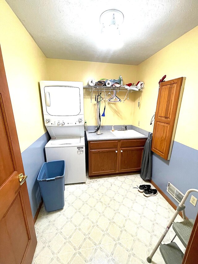 5753 Wood Valley Rd, Kalamazoo, MI 49009 - laundry area with stacked washing machine and dryer, cabinet space, a textured ceiling, and light flooring