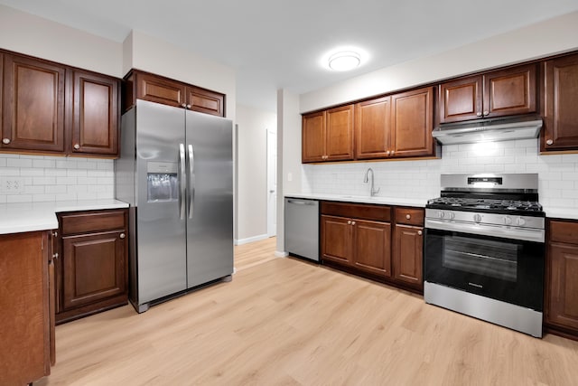 27152 Broadmoor Dr, Warren, MI 48088 - kitchen with appliances with stainless steel finishes, under cabinet range hood, light wood-style flooring, light countertops, and backsplash