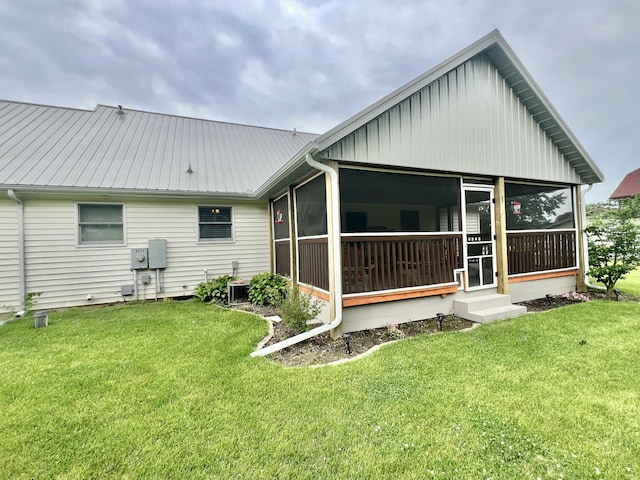 755 Tomahawk Trl, Coldwater, MI 49036 - rear view of property featuring a sunroom, a lawn, a metal roof, entry steps, and board and batten siding