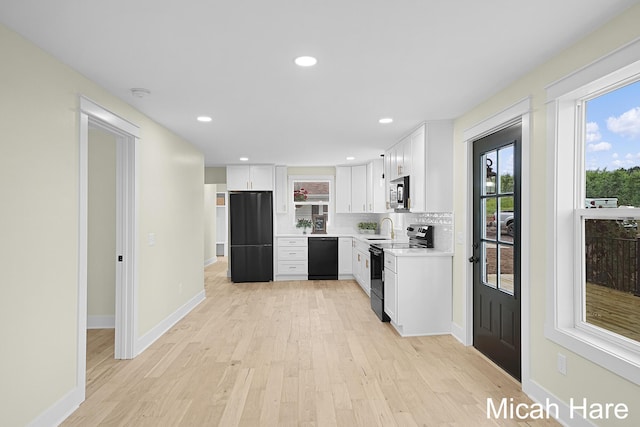 3054 Sehler St, Conklin, MI 49403 - kitchen featuring black appliances, light wood-type flooring, light countertops, white cabinetry, and tasteful backsplash