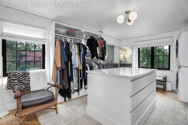 753 Grand Marais St, Grosse Pointe Park, MI 48230 - spacious closet featuring stacked washer and clothes dryer, light wood-style flooring, and a chandelier