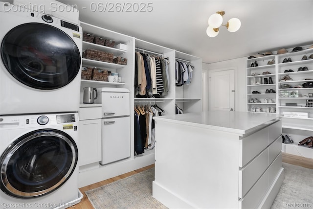 753 Grand Marais St, Grosse Pointe Park, MI 48230 - laundry room featuring stacked washer and clothes dryer, cabinet space, and light wood-type flooring
