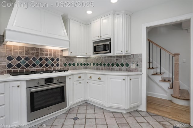 753 Grand Marais St, Grosse Pointe Park, MI 48230 - kitchen with stainless steel appliances, custom range hood, light countertops, white cabinets, and recessed lighting