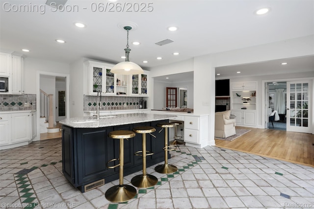 753 Grand Marais St, Grosse Pointe Park, MI 48230 - kitchen featuring recessed lighting, glass insert cabinets, white cabinetry, stainless steel microwave, and tasteful backsplash