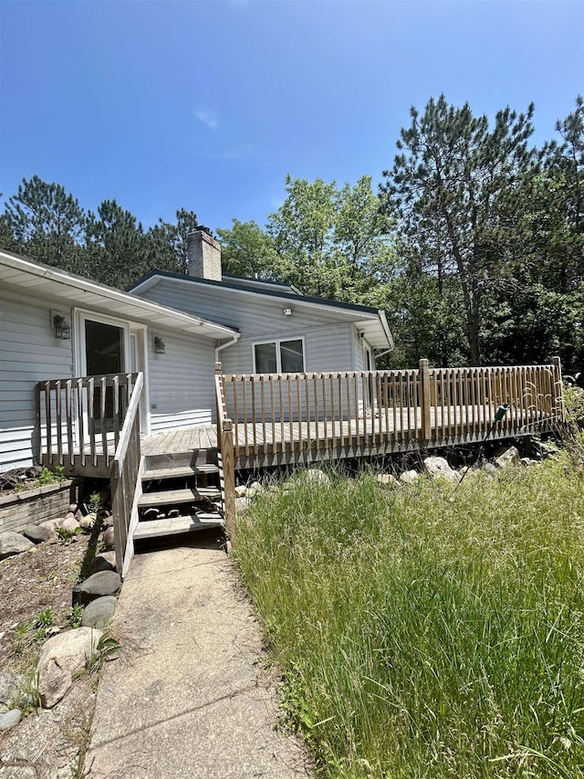 218 W Stover Rd, Standish, MI 48658 - view of side of home featuring a deck, a chimney, and driveway