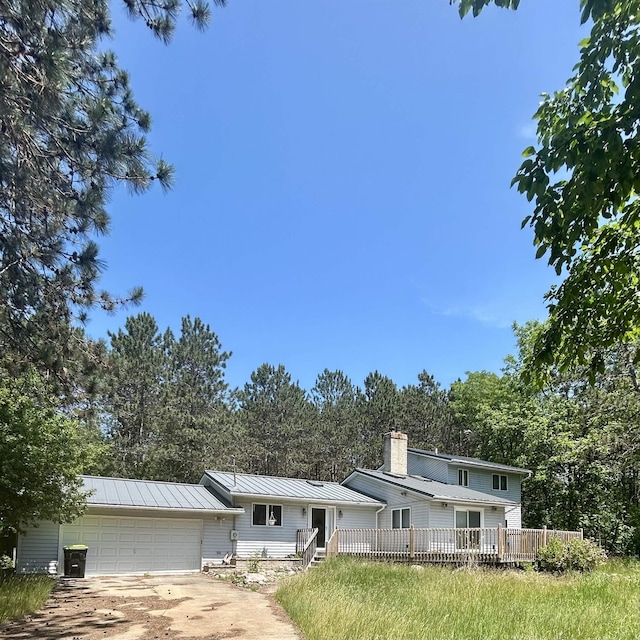 218 W Stover Rd, Standish, MI 48658 - view of front of home featuring a garage, concrete driveway, a chimney, a metal roof, and a standing seam roof
