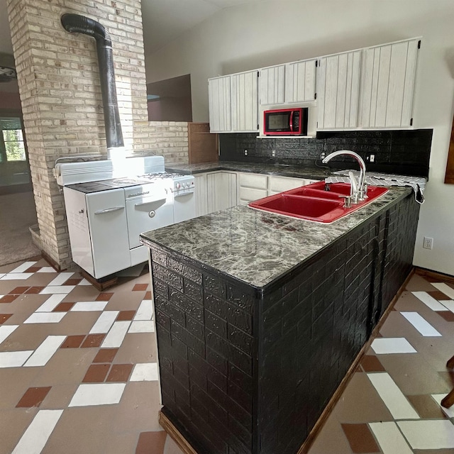218 W Stover Rd, Standish, MI 48658 - kitchen with dark flooring, dark countertops, decorative backsplash, a wood stove, and a peninsula