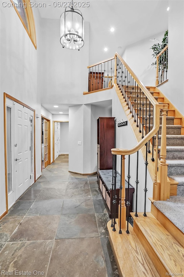 2300 Canyon Ridge Dr, White Lake, MI 48383 - entryway featuring a towering ceiling, stone finish floors, stairway, a chandelier, and recessed lighting