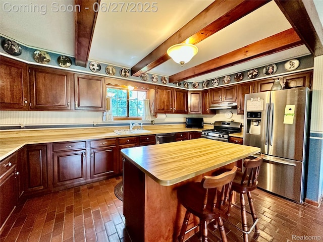 9276 Old Plank Ln, Brighton, MI 48114 - kitchen with appliances with stainless steel finishes, butcher block counters, under cabinet range hood, brick flooring, and beam ceiling