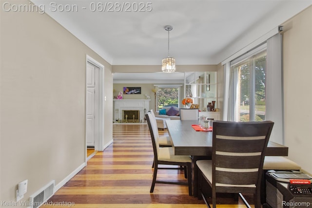 21415 Lathrup St, Southfield, MI 48075 - dining area featuring light wood finished floors, a fireplace, and a chandelier